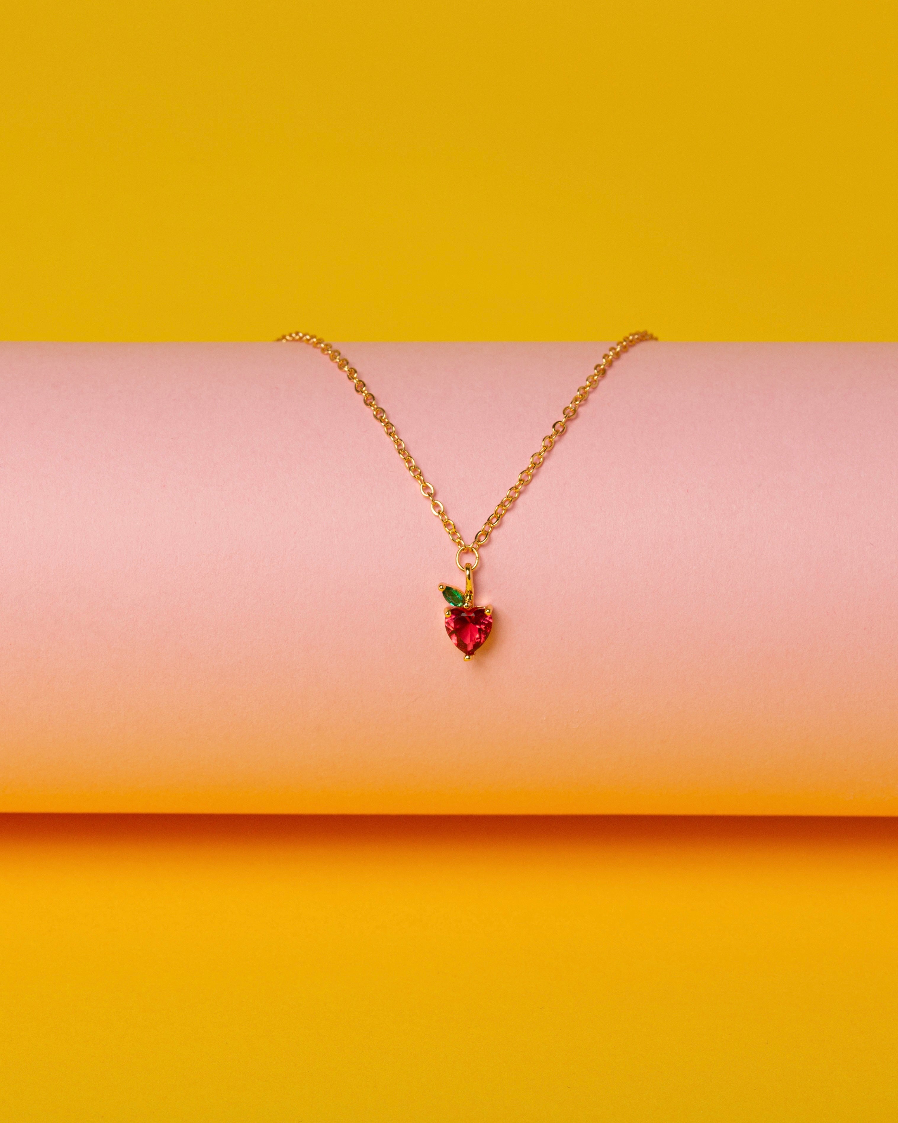 Dettaglio della collana pendente mela su sfondo rosa e giallo, placcata in oro 18 carati, Fruits & Jewels