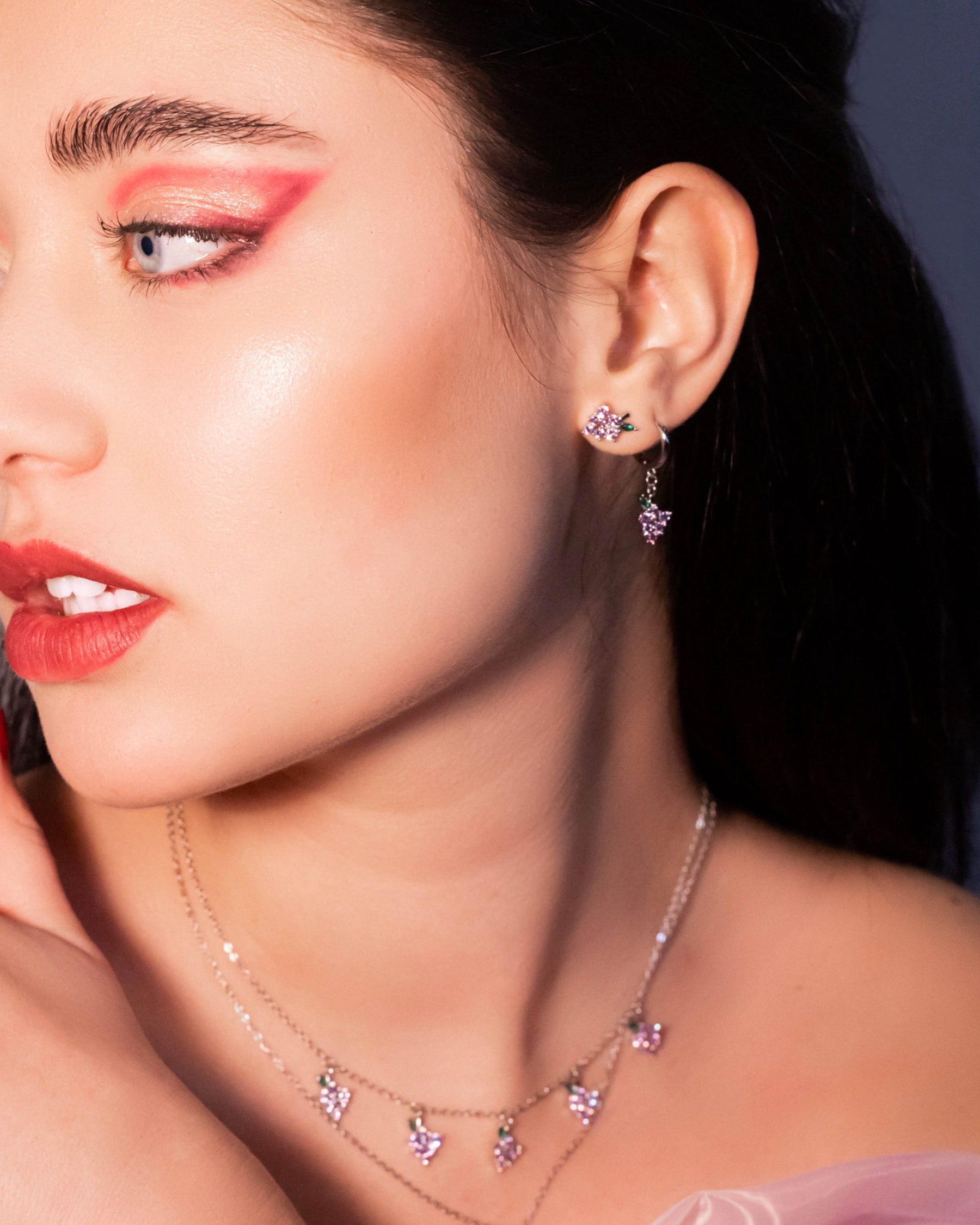 Dettaglio degli orecchini pendenti uva in argento Fruits & Jewels con zirconi lilla, abbinati a una collana con charms coordinati. Il design elegante e brillante dona luce al viso con un tocco sofisticato.