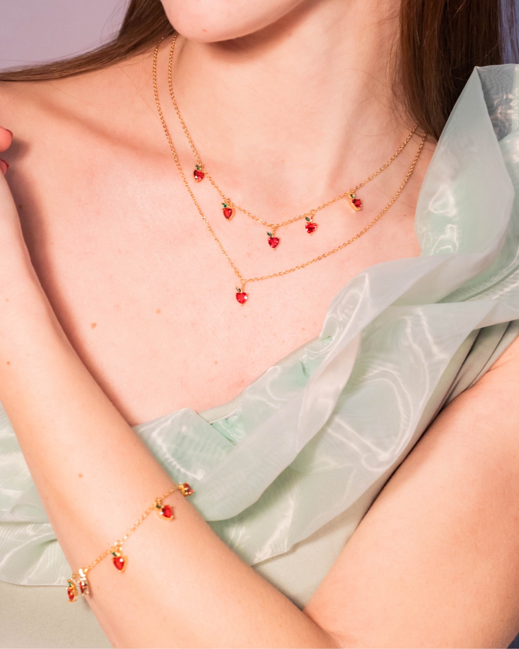 Dettaglio della collana con charms mela placcata in oro 18 carati a due fili, indossata insieme a bracciale coordinato, Fruits & Jewels
