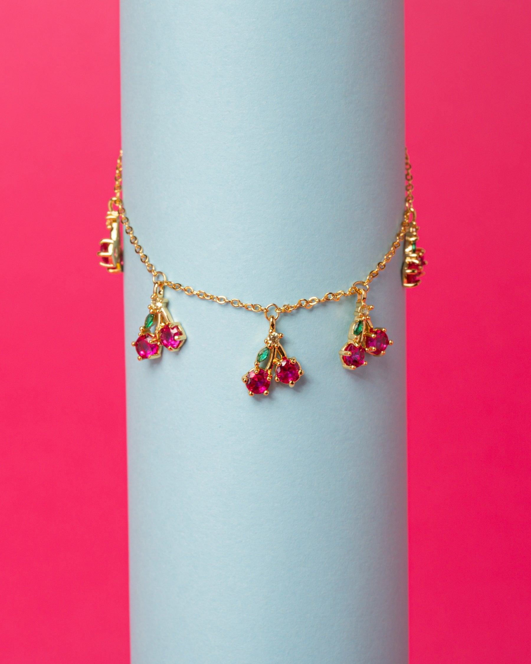 Bracciale ciliegia placcato oro su sfondo rosa e azzurro – design fruttato e vivace Fruits & Jewels