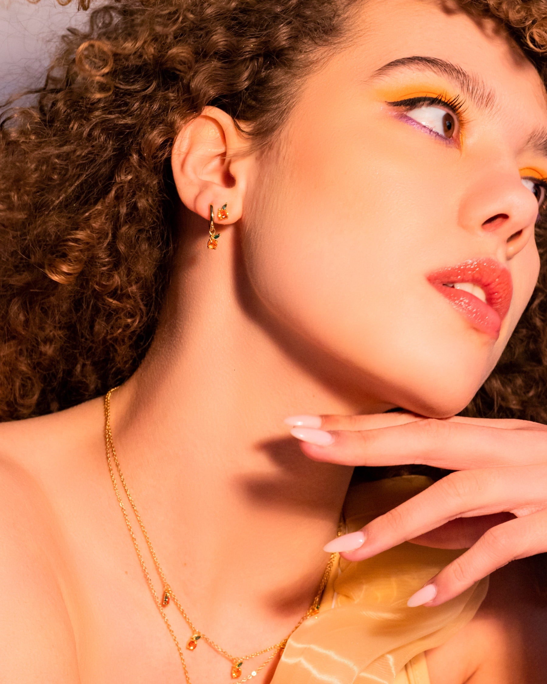 Orecchino pendente arancia placcato oro 18 carati Fruits & Jewels indossato da modella con collana abbinata e trucco giallo-arancio