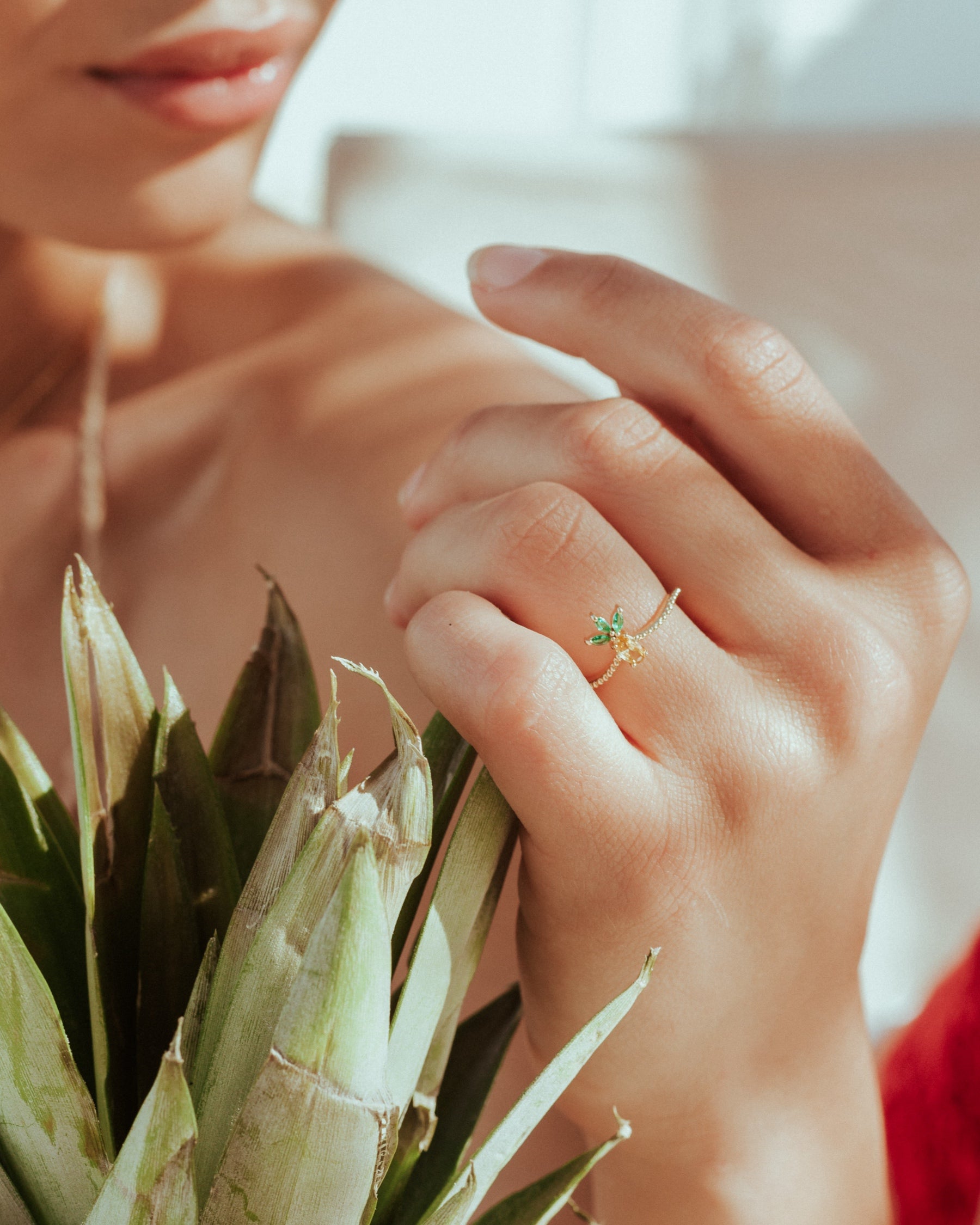 Anello con charm ananas placcato in oro 18 carati – indossato con outfit rosso e ananas tra le mani