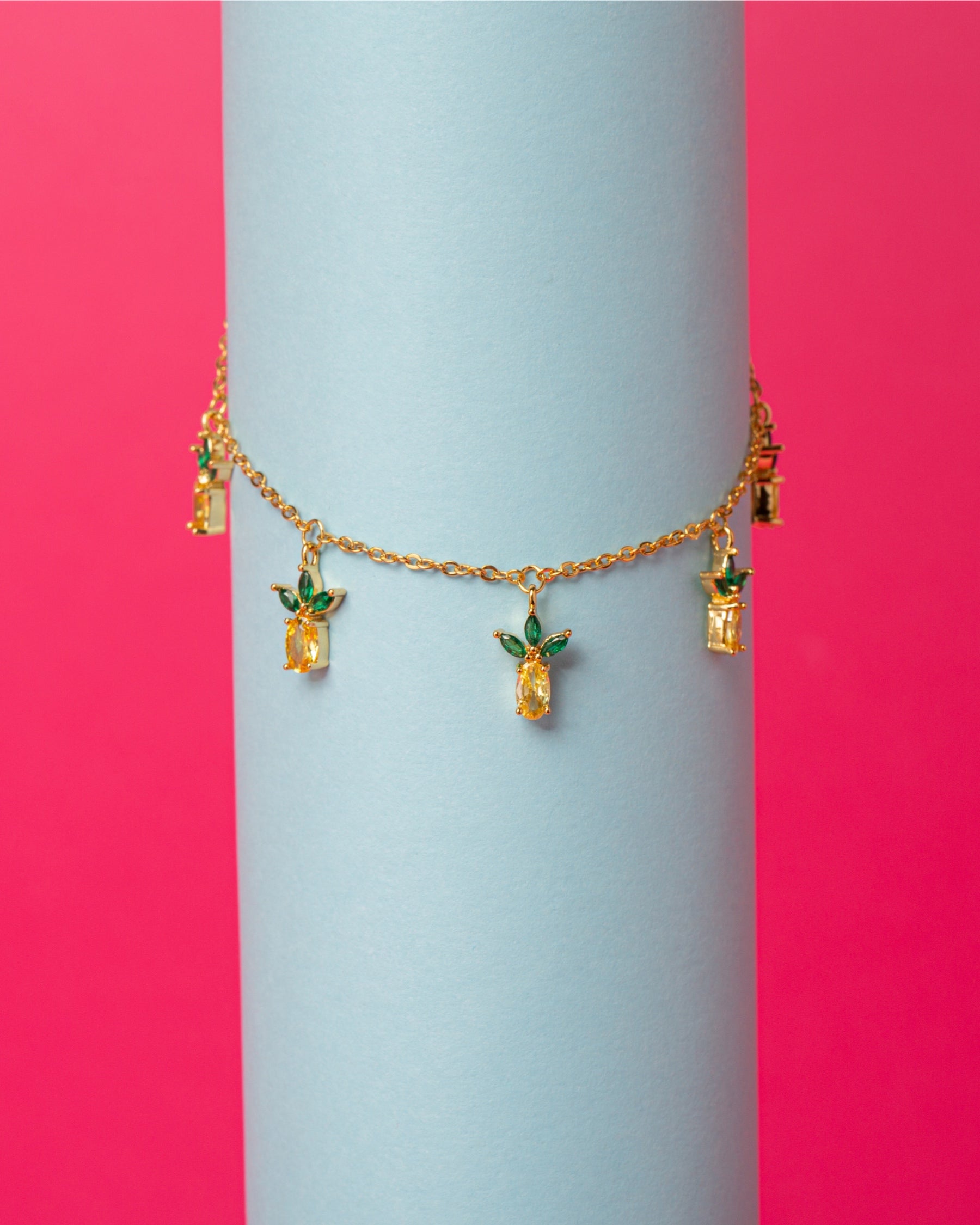 Bracciale con charm ananas placcato in oro 18 carati – presentato su sfondo colorato