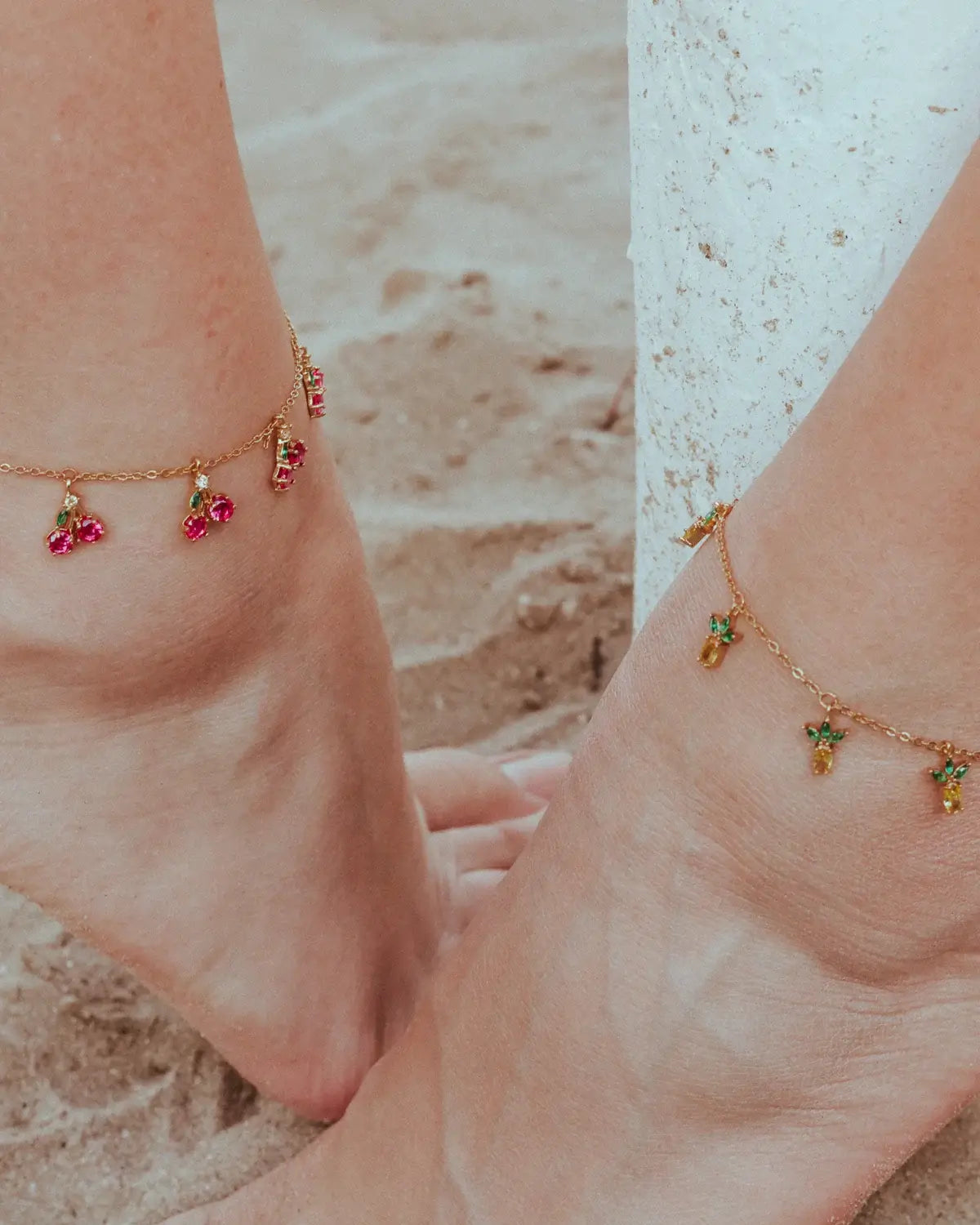 Cavigliera con charms a forma di ciliegia in oro 18k indossata su piedi nella sabbia – gioielli fruttati estivi di Fruits & Jewels
