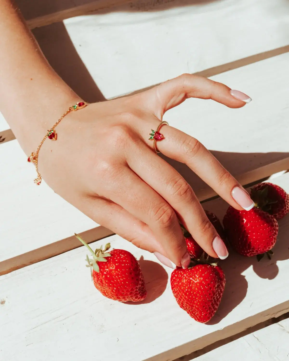 Bracciale con pendenti a forma di fragola su mano femminile – stile dolce e colorato by Fruits & Jewels