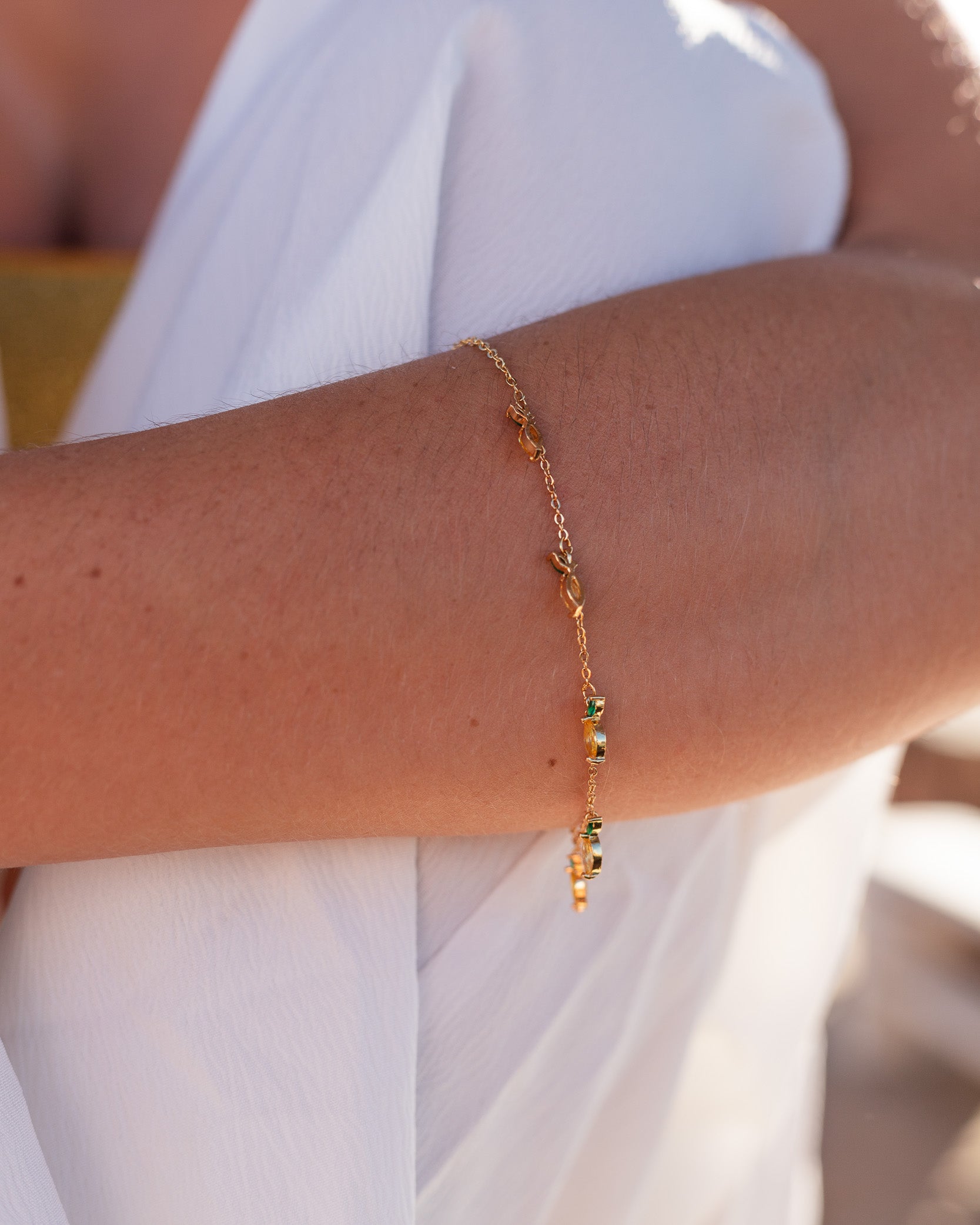 Dettaglio del bracciale limone placcato oro su braccio di modella seduta – design leggero e dorato per look estivi Fruits & Jewels
