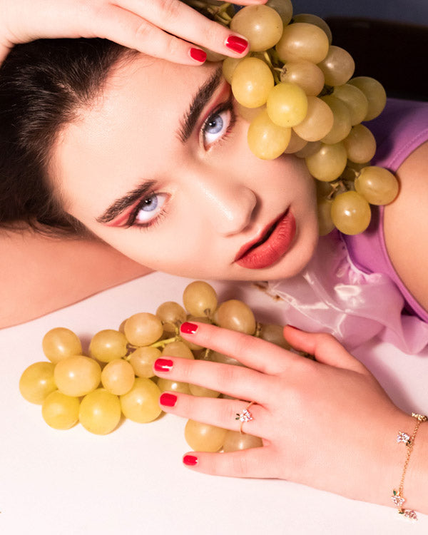 Primo piano dell’anello uva dorato Fruits & Jewels con dettaglio gioielli e frutti in stile glamour su sfondo chiaro