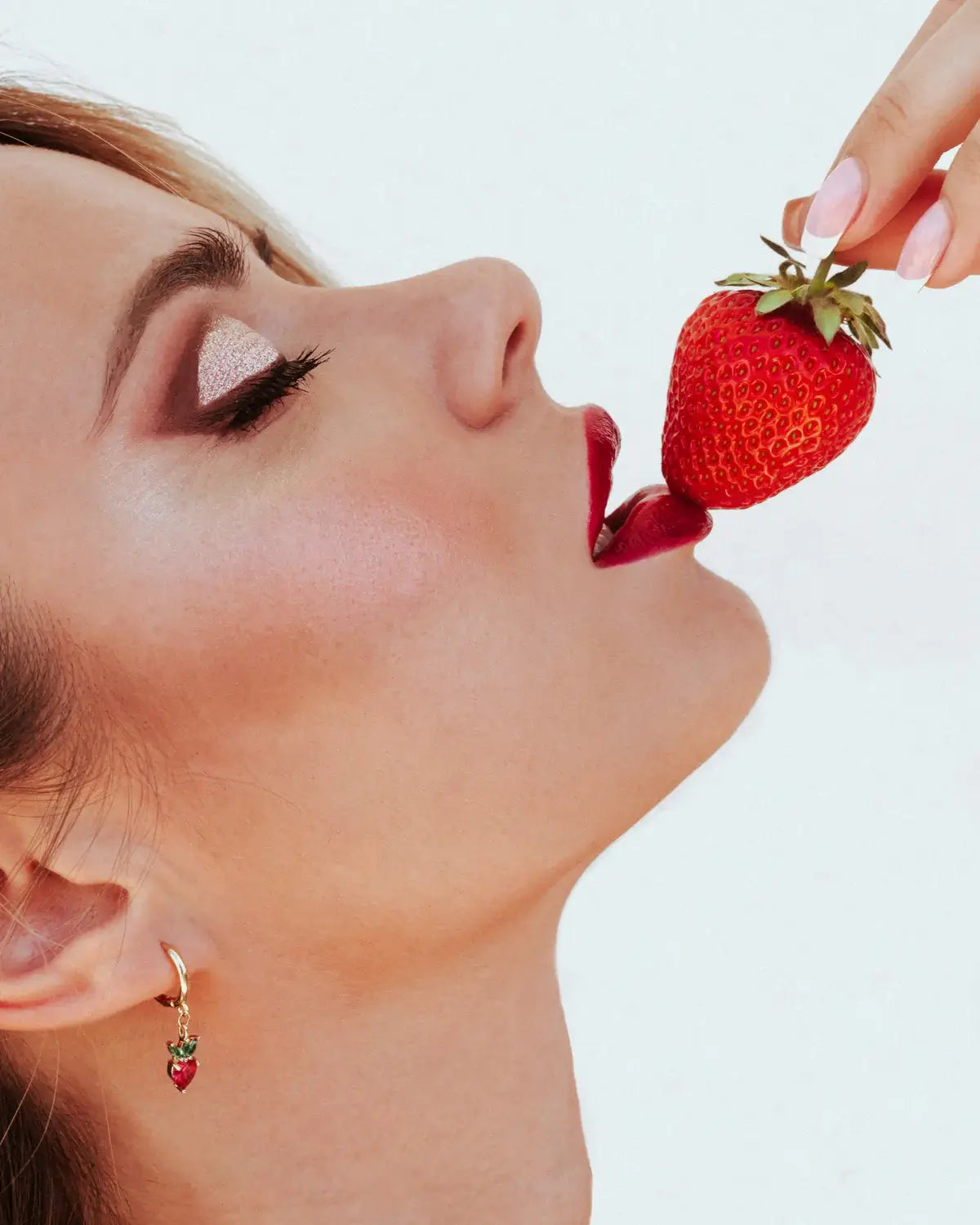 Dettaglio orecchino fragola placcato oro indossato da modella con fragola fresca – eleganza fruttata e giocosa by Fruits & Jewels