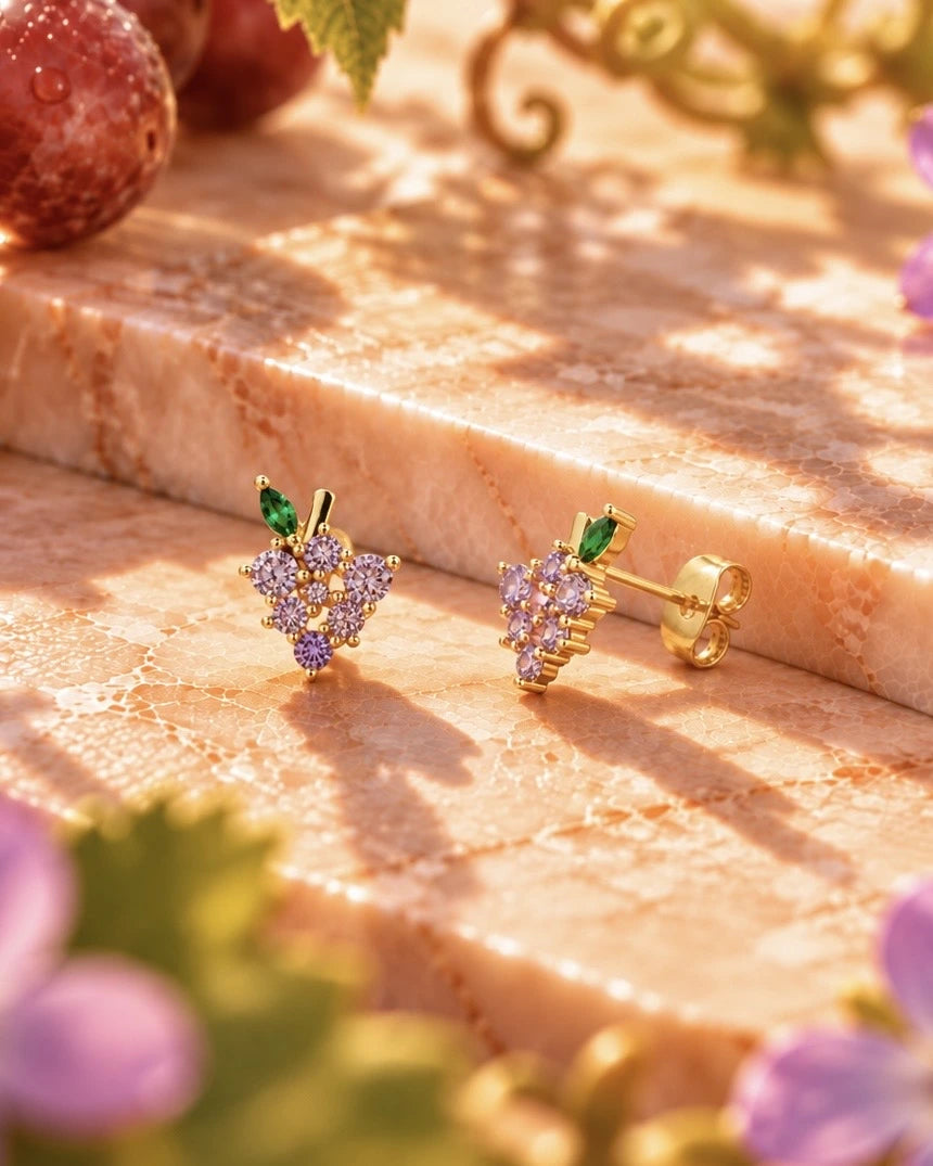 Orecchini lobo uva Fruits & Jewels poggiati su marmo. Gioielli frutta donna